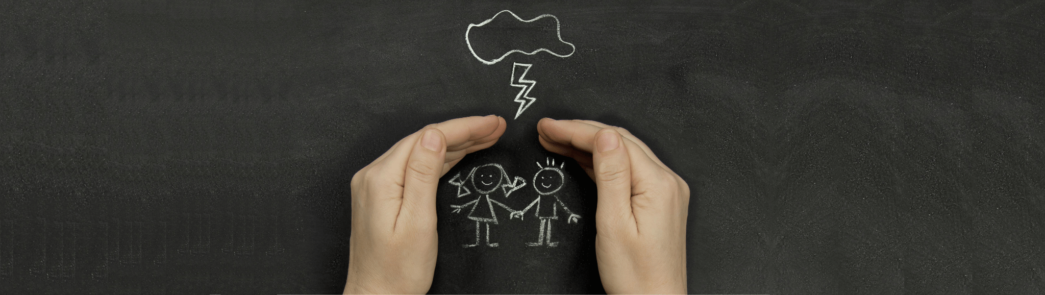 mani che si mettono in segno di protezione di due minori disegnati su una lavagna